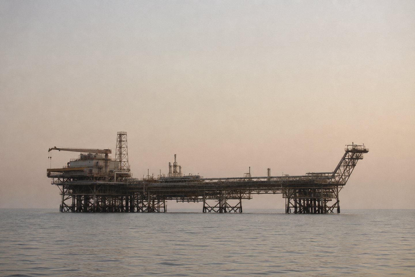 An offshore oil and gas production platform on flat water in the Persian Gulf at dawn